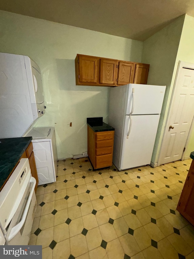 kitchen featuring stacked washing maching and dryer and white refrigerator