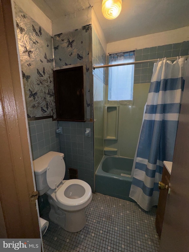 full bathroom with tile patterned floors, toilet, shower / bath combo with shower curtain, tile walls, and vanity