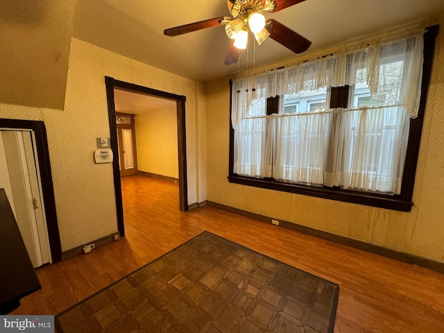 unfurnished room with a wealth of natural light, wood-type flooring, and ceiling fan