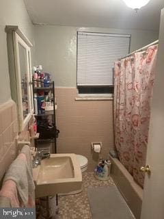 full bathroom with tile patterned floors, sink, toilet, shower / bathtub combination with curtain, and tile walls