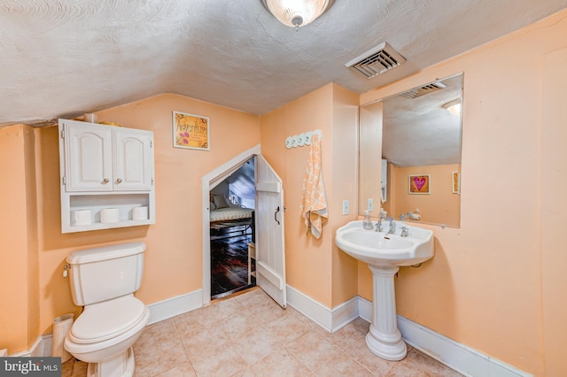 bathroom with toilet, a textured ceiling, and vaulted ceiling