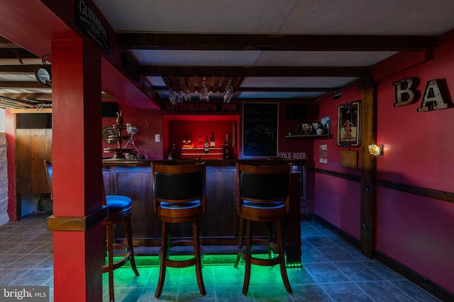 bar featuring beamed ceiling and dark tile patterned floors