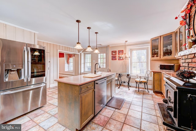 kitchen featuring hanging light fixtures, a center island with sink, crown molding, light tile patterned flooring, and appliances with stainless steel finishes