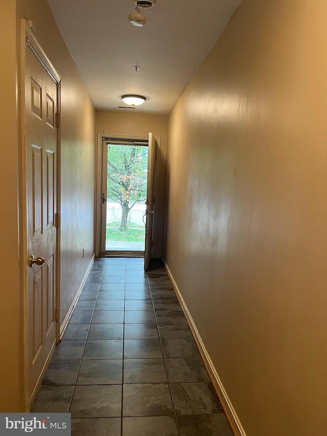 doorway to outside with dark tile patterned floors