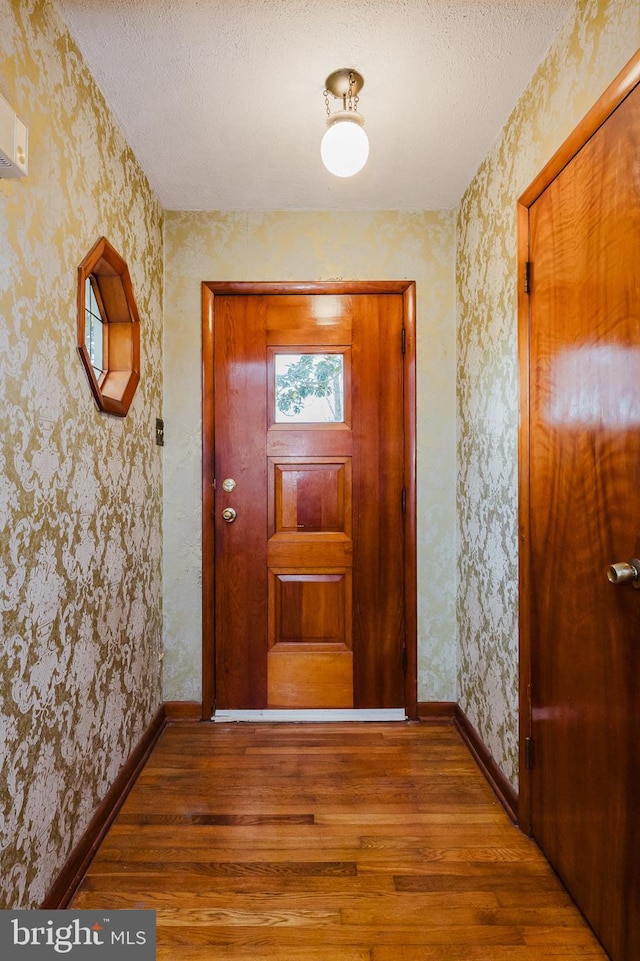 doorway to outside featuring wood-type flooring and a textured ceiling