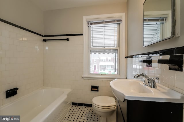 bathroom with a tub, vanity, tile walls, and toilet