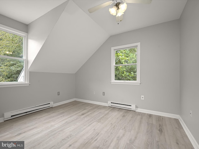 additional living space featuring baseboard heating, light hardwood / wood-style flooring, and a wealth of natural light