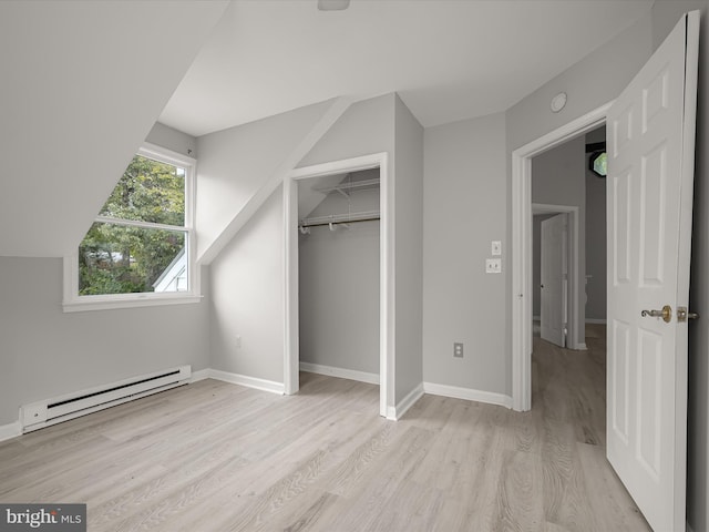 unfurnished bedroom featuring a baseboard heating unit, light wood-style flooring, and baseboards