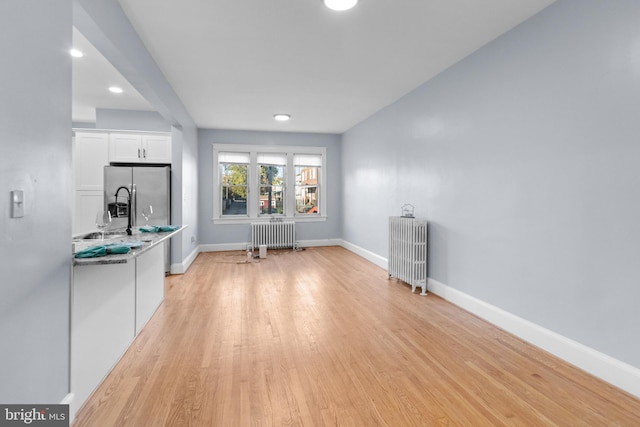 kitchen featuring white cabinets, stone countertops, radiator heating unit, and fridge with ice dispenser