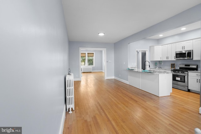 kitchen with white cabinets, radiator, and appliances with stainless steel finishes