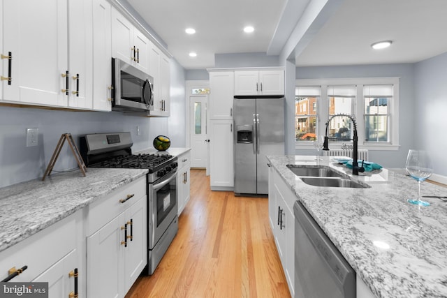 kitchen featuring light stone counters, sink, white cabinets, and stainless steel appliances