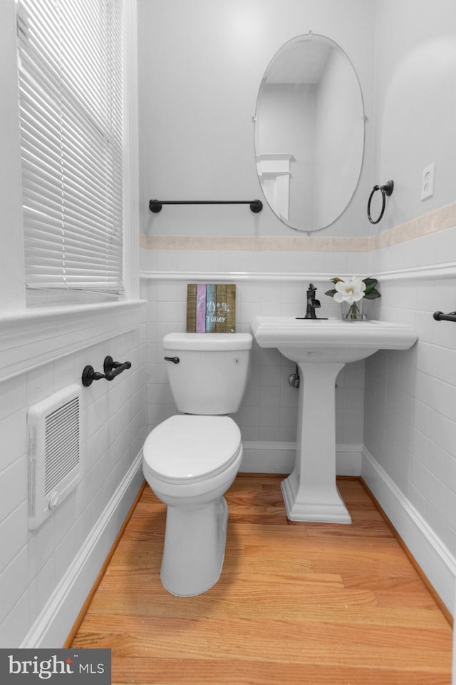 bathroom featuring hardwood / wood-style floors, tile walls, and toilet