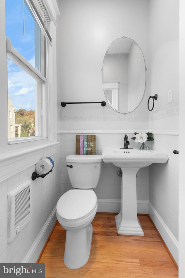 bathroom with hardwood / wood-style flooring, toilet, and tile walls