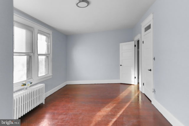 unfurnished room featuring dark hardwood / wood-style flooring and radiator heating unit