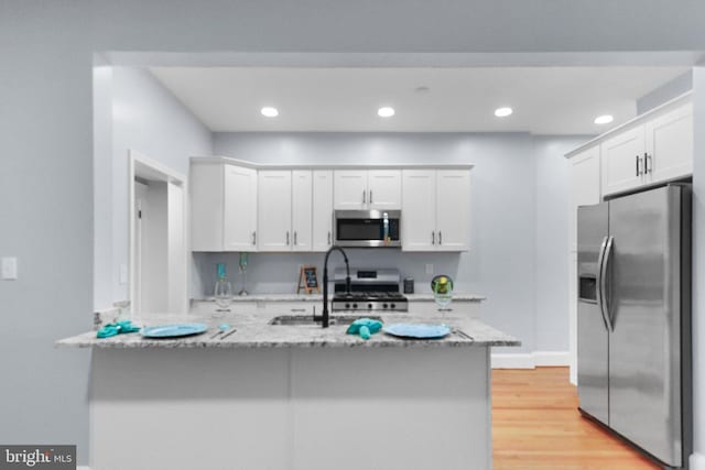 kitchen with light stone countertops, white cabinetry, and stainless steel appliances