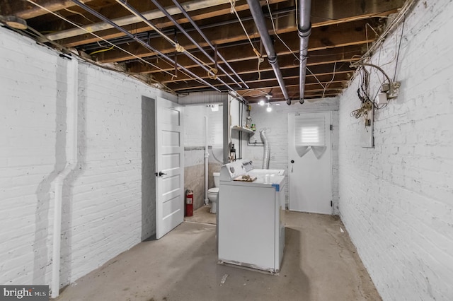 basement featuring washer / clothes dryer and brick wall