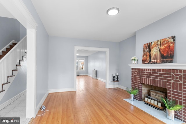 living room with light hardwood / wood-style floors and a brick fireplace