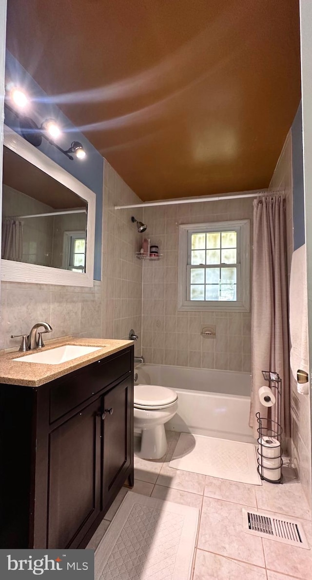 full bathroom with tile walls, toilet, vanity, shower / tub combo with curtain, and tile patterned floors