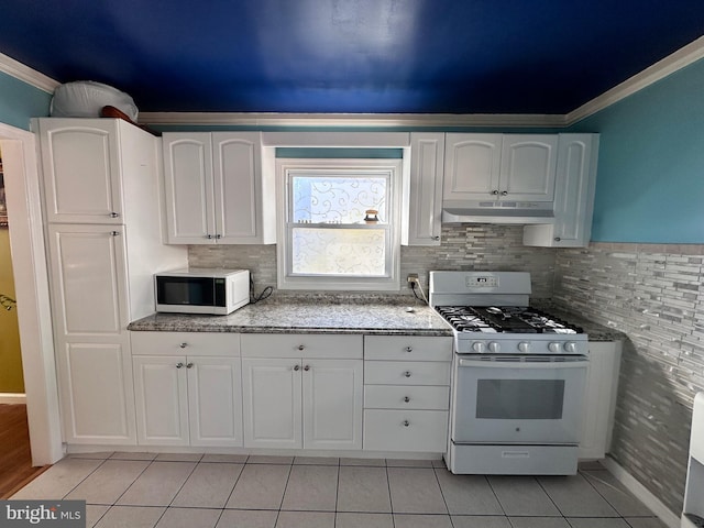 kitchen featuring white appliances, white cabinetry, light tile patterned floors, and ornamental molding