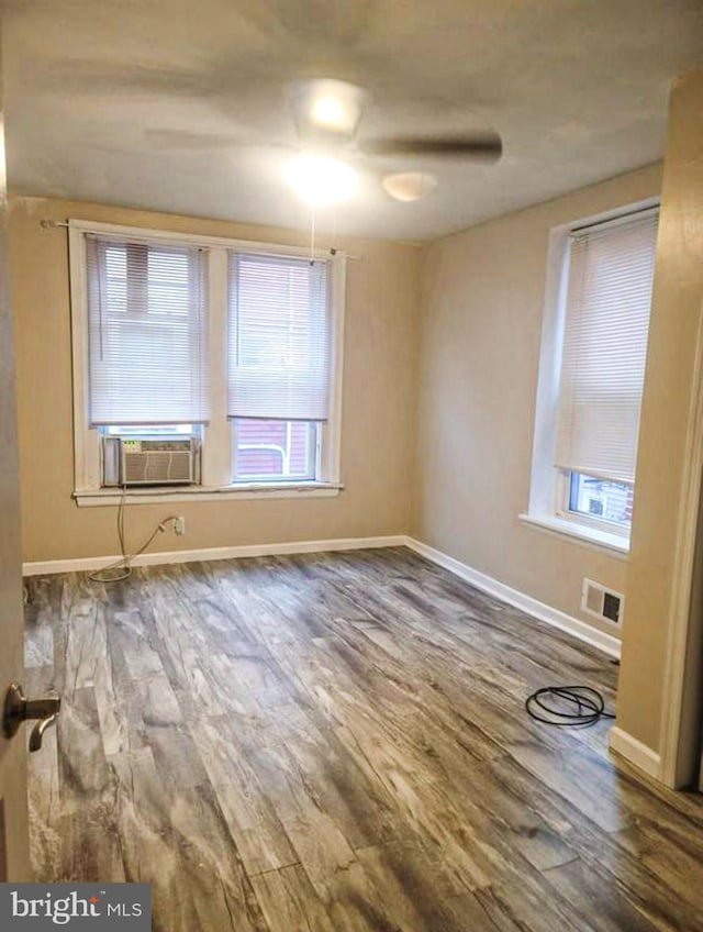 unfurnished room featuring cooling unit, wood-type flooring, and a wealth of natural light