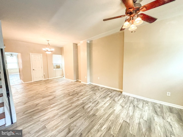 unfurnished living room with ceiling fan with notable chandelier and light wood-type flooring