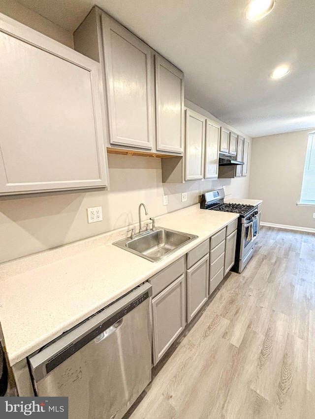 kitchen featuring appliances with stainless steel finishes, sink, light wood-type flooring, and gray cabinets