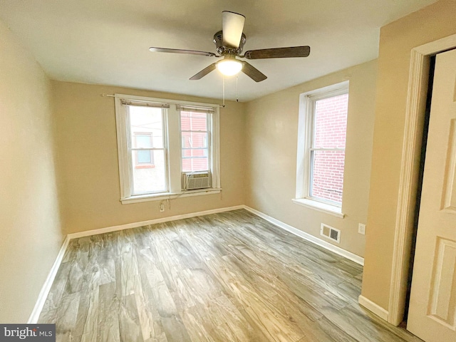 spare room with light hardwood / wood-style floors, cooling unit, and ceiling fan