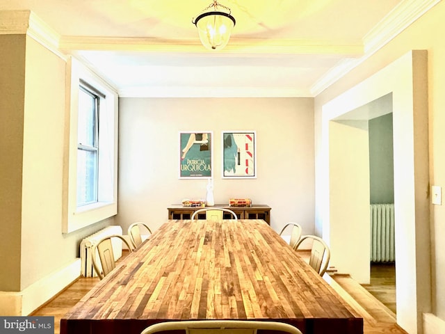 unfurnished dining area with wood-type flooring, radiator, beamed ceiling, and crown molding