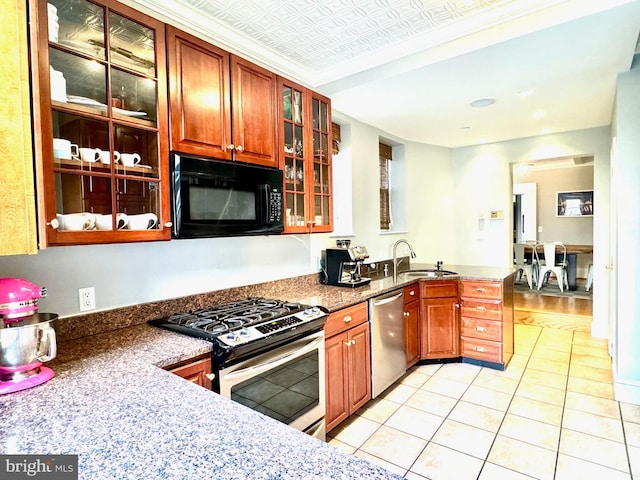 kitchen with dark stone countertops, appliances with stainless steel finishes, sink, and light wood-type flooring