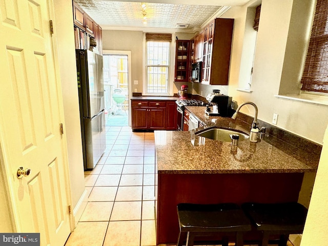 kitchen featuring light tile patterned flooring, stone counters, sink, and stainless steel appliances