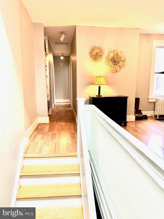 stairway featuring radiator heating unit and hardwood / wood-style floors