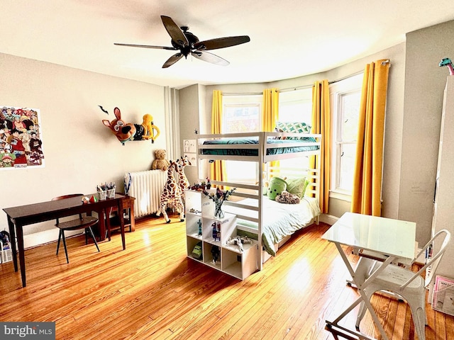 bedroom featuring ceiling fan, radiator, and light hardwood / wood-style floors