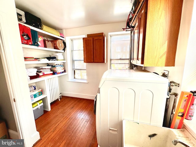 clothes washing area featuring hardwood / wood-style floors, cabinets, and washer / dryer