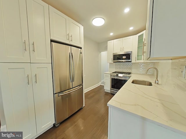 kitchen featuring appliances with stainless steel finishes, white cabinetry, sink, and light stone counters