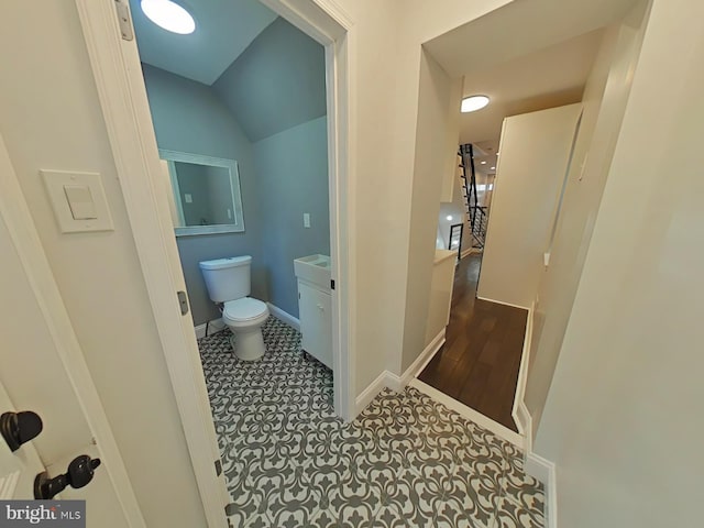 bathroom with vanity, vaulted ceiling, toilet, and tile patterned floors