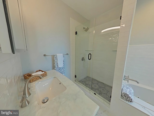 bathroom featuring plus walk in shower, sink, and tile walls