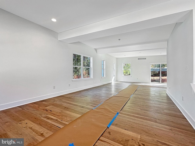 unfurnished living room featuring beam ceiling and hardwood / wood-style flooring