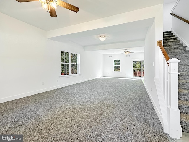 unfurnished living room featuring a wealth of natural light, ceiling fan, and carpet