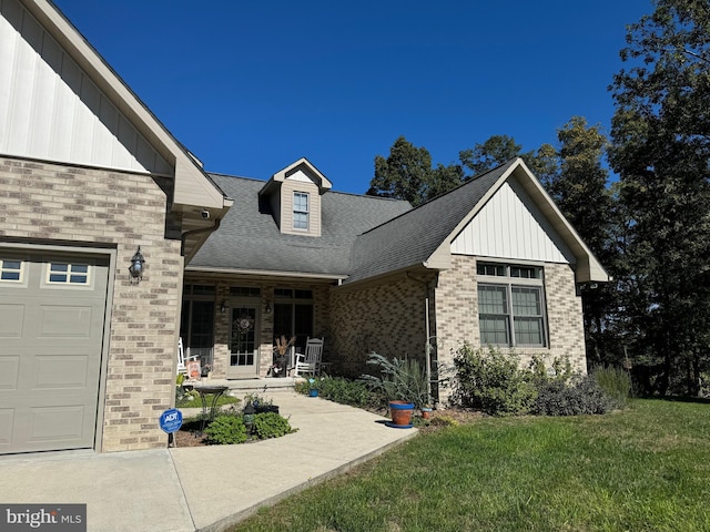 view of front of house with a garage, a front yard, brick siding, and a shingled roof