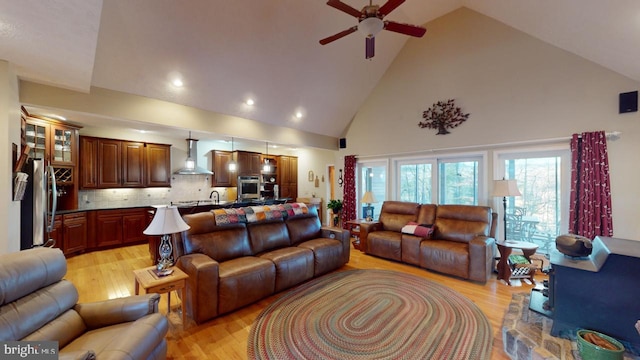 living room featuring high vaulted ceiling, light wood finished floors, and a ceiling fan