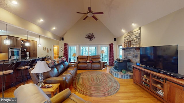 living area with high vaulted ceiling, a ceiling fan, and light wood-style floors