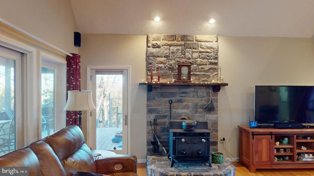 living room featuring a wood stove, wood finished floors, and lofted ceiling