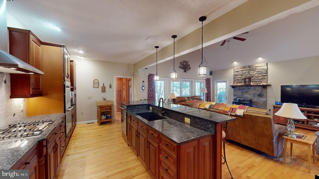 kitchen featuring tasteful backsplash, a breakfast bar area, appliances with stainless steel finishes, open floor plan, and a sink