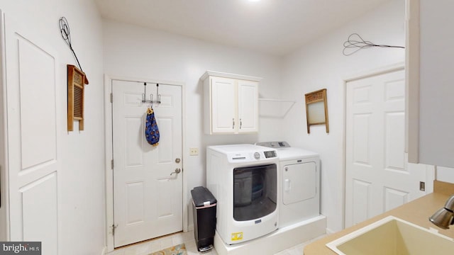 clothes washing area featuring cabinet space, a sink, and independent washer and dryer