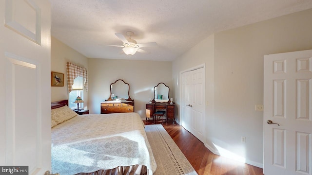 bedroom featuring a textured ceiling, dark wood-style flooring, a ceiling fan, baseboards, and a closet