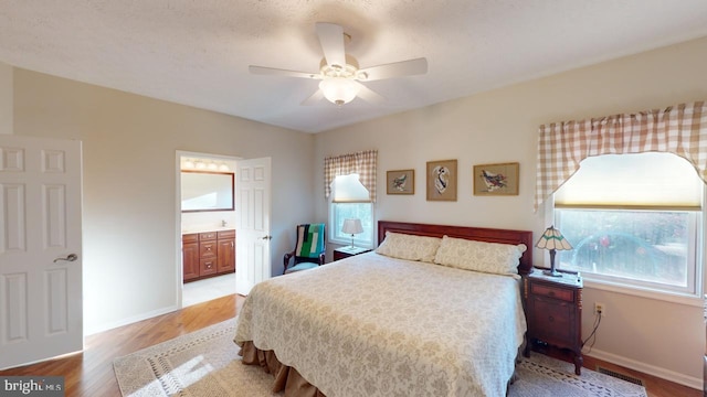 bedroom with baseboards, connected bathroom, light wood finished floors, and ceiling fan