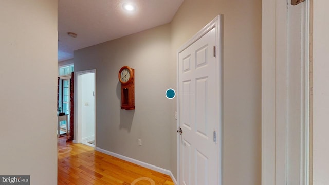 corridor with light wood finished floors and baseboards