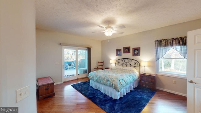 bedroom featuring a textured ceiling, ceiling fan, baseboards, access to exterior, and hardwood / wood-style floors