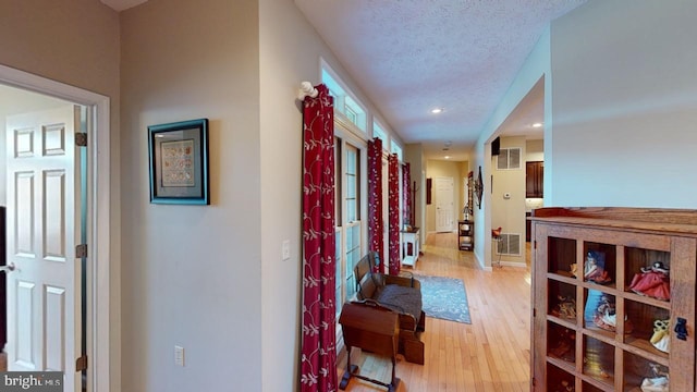 corridor with a textured ceiling, recessed lighting, visible vents, and light wood-style floors