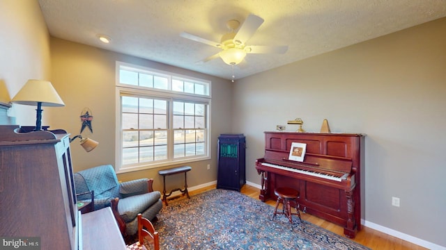 sitting room featuring ceiling fan, a textured ceiling, baseboards, and wood finished floors